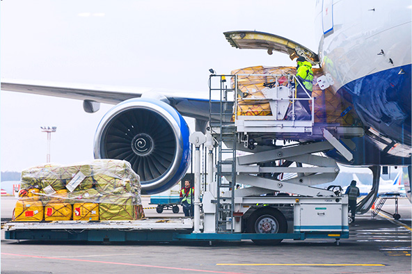 Avião azul e branco na pista de um aeroporto sendo carregado com diversas sacas amarelas. Um exemplo de transporte multimodal.